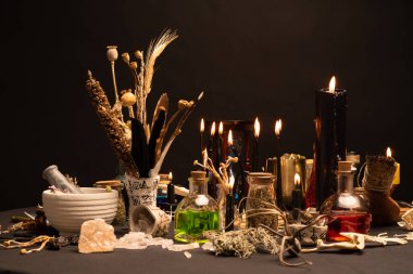 Büyücülük, siyah yanan mumlarla dolu seçici bir odak noktasıdır. Cadılar Bayramı için esrarengiz gotik ve okült cadı masası. Çeşitli sihirli nesneler ve ayin düzenlemeleri. Gotik Cadılar Bayramı. 