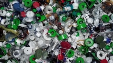 Plastik şişe parçaları, bardaklar, mantarlar, pipetler, su ve şampuan şişeleri, krem ambalajlar ve masaya atılan diğer bir kerelik çöpler. Çevre kirliliği, geri dönüşüm, atık yönetimi sorunu.