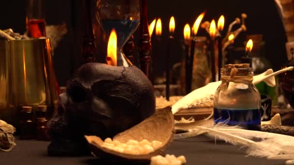 魔女の儀式用テーブルに魔法の工芸品が並んでいます 前面の選択的フォーカス 黒い魔法のカラスやカラスのつま先でまだ生活 動物の骨 ポーションバイアルと儀式乾燥セージ雑草 ゴシックハロウィンのコンセプト — ストック動画