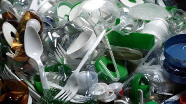 Plastik şişe parçaları, bardaklar, mantarlar, pipetler, su ve şampuan şişeleri, krem ambalajlar ve masaya atılan diğer bir kerelik çöpler. Çevre kirliliği, geri dönüşüm, atık yönetimi sorunu.