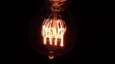 Edison ampulü yavaş yavaş odak ve detaylarla ortaya çıkar. Vintage filament ampulün altında kayarak alttaki makro görüntüyü bokeh efektiyle parlıyor ve parlatıyor. 4K.