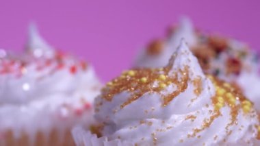 Cupcakes makro yüzeysel alan görüşü derinliği. Süslü şekerli fincanlar, pembe arka planda beyaz vanilya kremalı kekler. Lezzetli çörekler kız doğum günü veya sevgililer günü için..