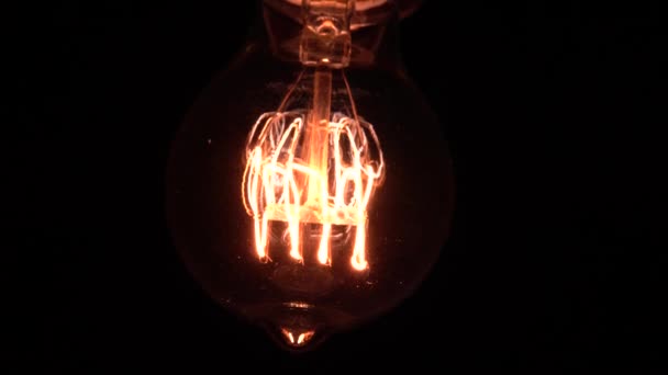 Edison glödlampa avslöjar långsamt i fokus och detaljer. Glider under vintage glödlampa glöder och lysa upp närbild makro vy underifrån med bokeh effekt. 4K. — Stockvideo