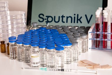 Toronto, Ontario, Kanada - 20 Nisan 2021: Sputnik V aşı adı bulanık ve içinde Gam-COVID-Vac içeren şırıngalar bulunan şişeler. Rus Coronavirus aşısı konsepti. Sığ alan derinliği.