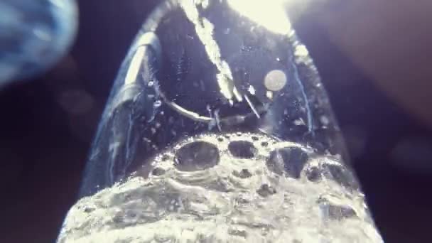 下からガラス越しに清らかな輝く水を注ぎます 選択的フォーカスが閉じます 水の流れはガラスの気泡とスプラッシュと渦を移動します 清新な湧き水で水分補給 — ストック動画
