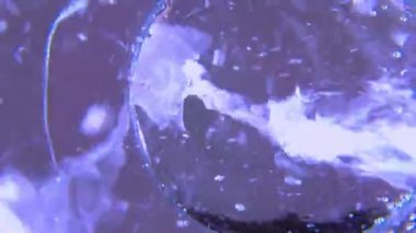 Kavanozdan bir bardağa saf, köpüklü su dökülüyor. Seçici odak, aşağıdan yaklaş. Su akıntısı hareket eder ve camda hava kabarcıklarıyla kıvrılır. Temiz kaynak suyuyla sulandırma.