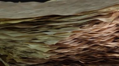 Ahşap masada eski parşömen kağıtları dönüyor, eski yanmış kağıt stokları. Kaligrafi biyografisi kayıtları ve kitap hazırlama için kağıt. Seçici odak.
