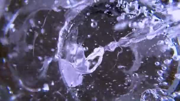 Дно стакана воды. Вода наливается в стекло из кувшина или кувшина замедленной съемки. Супер макрос закрывает избирательный фокус. Пузыри и водовороты в стакане. Вид снизу. — стоковое видео