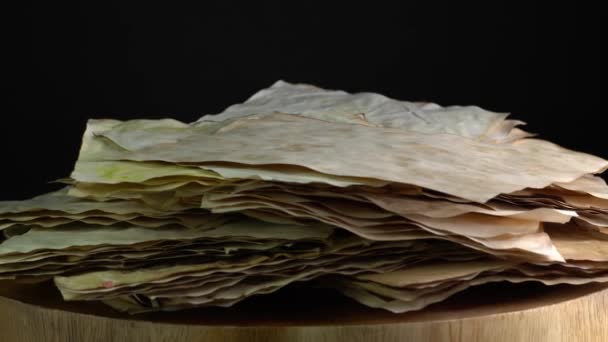 Starověké pergamenové papíry rotující na dřevěném stole, stará ošlehaná spálená zásoba papíru. Papír pro kaligrafické záznamy a tvorbu knih. Selektivní zaměření. — Stock video