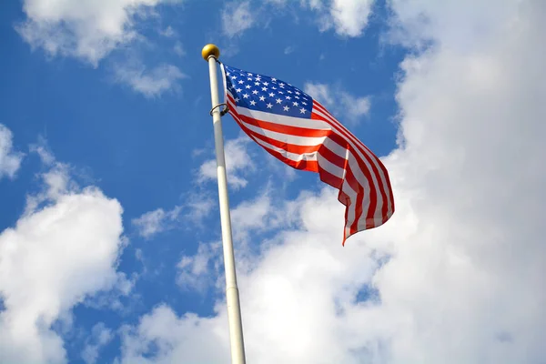 青空にアメリカの国旗 アメリカの国旗は 夏の空と雲とポールにかかっています フィルター処理していない 自然な照明 — ストック写真