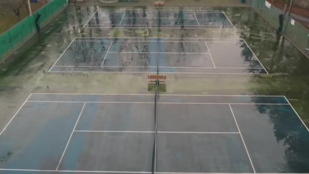 Aerial top view and movement over tennis court. Slow flying above empty tennis stadium. Rainy summer day. — стоковое видео