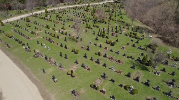 Zweef boven de moderne Amerikaanse begraafplaats. Veel grafstenen en stenen kruisen op de begraafplaats van de stad. Zonnige lentedag. Uitzicht vanuit de lucht op graftombes van bovenaf. — Stockvideo