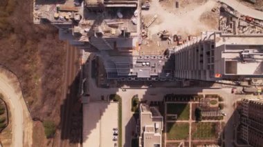 Boş inşaat sahasına, vinçlere ve makinelere, şehir merkezindeki araba trafiğine bakın. Havadan görünüşlü. Yeni konut inşaatı beton çerçeveli. Kentsel çok katlı apartman.