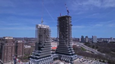 Aerial flight near and around new constructions building development site. Modern architecture of skyscrapers and high rise housing. Real Estate concept. Empty working area, cranes and heavy machinery