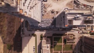 View over empty construction site, cranes and machinery, car traffic in city downtown. Aerial top view. New residential housing construction concrete framing. Urban multi-storey apartment building.