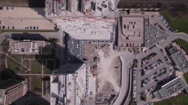 View over empty construction site, cranes and machinery, car traffic in city downtown. Aerial top view. New residential housing construction concrete framing. Urban multi-storey apartment building.