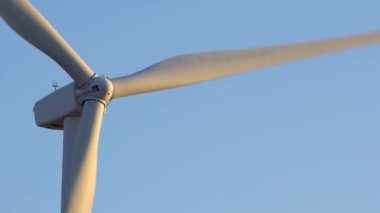 Aşağıdan rüzgar türbini güç istasyonuna yakın çekim. Çevre mühendisliği ve yenilenebilir enerji. Akşamları mavi gökyüzü ve altın saatinde telefoto lensleriyle rüzgâr değirmenlerinin manzarası