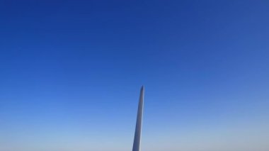 Rüzgar türbininin havada yakın çekim görüntüsü. Rüzgar tarafından dönüyor ve yenilenebilir yeşil enerji üretiyor. Altın saat günbatımında bir rüzgar türbinine yaklaşıyoruz. Enerji alternatifi ve çevre ekolojisi.