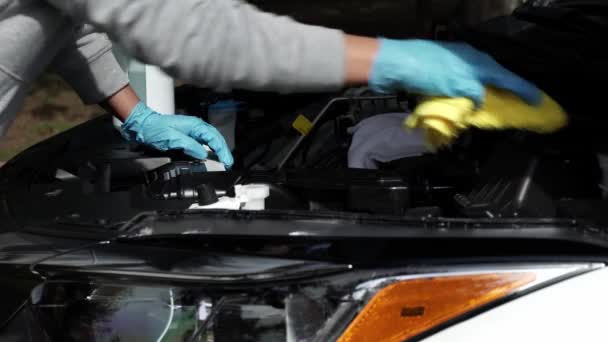 Primer plano de una mujer lavándose las manos y limpiando el coche con tela. Lavado y limpieza del compartimento del motor del vehículo o del concepto de servicios de detalle del coche. — Vídeo de stock