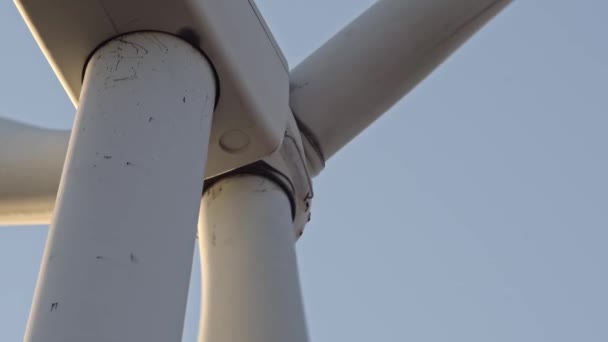 Close up shot of wind turbine power station from below. Environmental engineering and renewable energy. Scenic view of windmills turbine with blue sky in the evening with telephoto lens at golden hour — ストック動画
