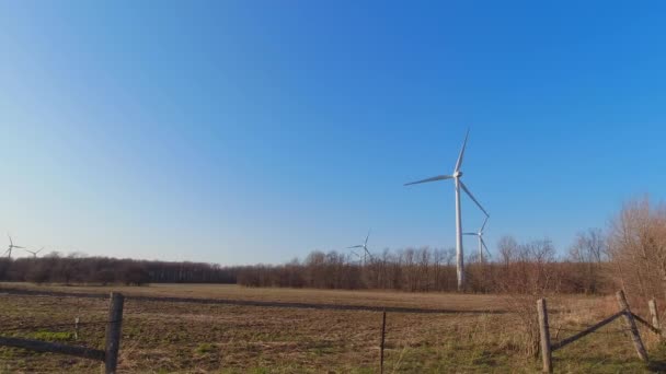 Turbina eólica con palas en la vista del paisaje de campo. Cielo azul con panorama de granja. Granja de molinos de viento que genera energía verde. Energía alternativa sostenible. Movimiento lento. — Vídeos de Stock