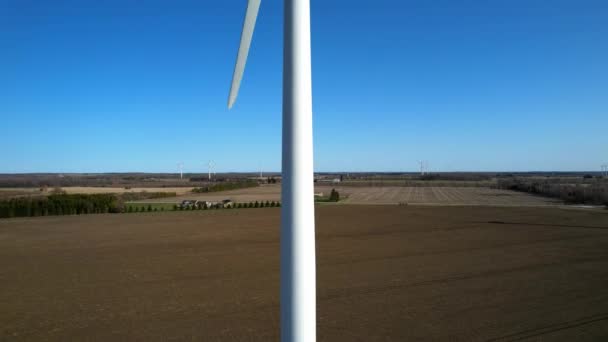 Велика вітрова турбіна з лопатями в польовому повітрі. Блакитне небо з панорамою ферм. Ферма вітряних млинів виробляє зелену енергію. Стала альтернативна енергія. Повільний рух . — стокове відео
