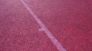 Suni spor alanı yüzeyi, güneşli bir günde beyaz çizgiler ve işaretler, koşmak için yol. Oyunlar ve etkinlikler için boş spor stadyumunun huzuru.