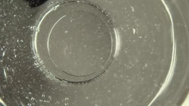 Güvensiz musluktaki kir bardakta sürükleniyor, aşağıdan görünüyor. Su krizi. Kötü yaşam koşulları ve temiz suya erişimi yok. Yerli halkın yoksulluğu ve eşitsizliği. Yavaş çekim.