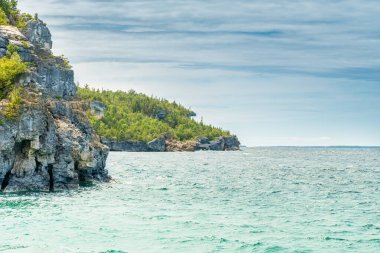 Bruce Peninsula Ulusal Parkı 'ndaki Huron Gölü' ndeki Indian Head Cove 'daki renkli yeşil sular ve Kanada' nın Ontario kentindeki berrak mavi su. The Grotto ve Overhang rock turistleri arasında yer alıyor.. 