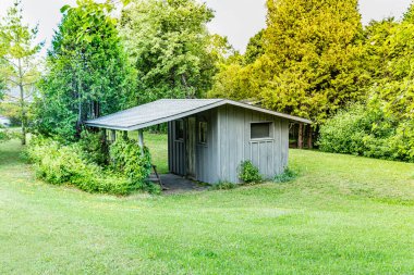 Küçük, eski, yıpranmış ahşap kulübe ya da ormanın yakınında ve Pike Körfezi 'ndeki Huron Gölü kıyılarında yaz günü yeşil köknar ağaçları ve sulak sularla çevrili.. 