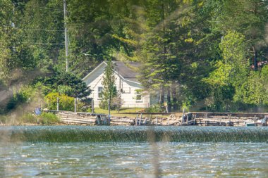 Uzun mesafe ve çok sıcak yaz havası, sahile vuran ahşap evler ve ağaçlar, su ve mavi gökyüzü ile manzarada jöle etkisi yaratıyor. Yaz tatili için göldeki kır evi.. 