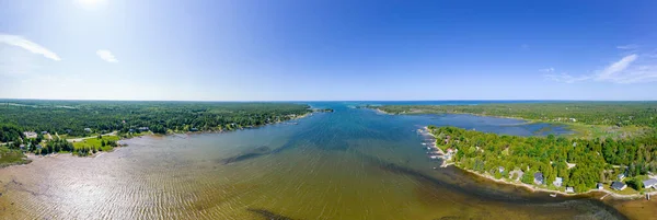 Lake at summer with wooden cottages and log cabins at the lakeshore in North America. Rural area view with green forest and lake in peninsula. Fishing Lodge at waterfront an summer huts with terrace.