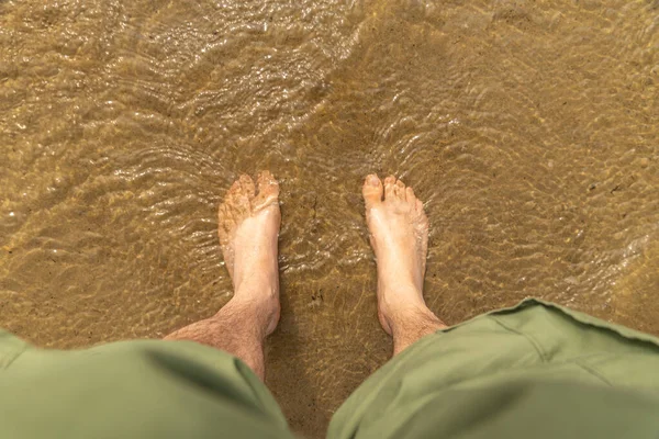 Tourist cooling his legs after hiking in Singing Sands shallow waters, Bruce Peninsula National Park Ontario Canada. Sandy beach Lake Huron, named after the sound the wind makes whistling in the dunes