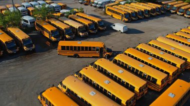 Toronto, Ontario, Canada - September 1, 2022: School bus vehicles ready for school educational season. Top view of parking yard with yellow trucks and evening sky, ready to pick up and drop off kids.