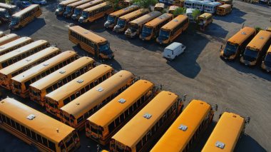 Toronto, Ontario, Canada - September 1, 2022: School bus vehicles ready for school educational season. Top view of parking yard with yellow trucks and evening sky, ready to pick up and drop off kids.