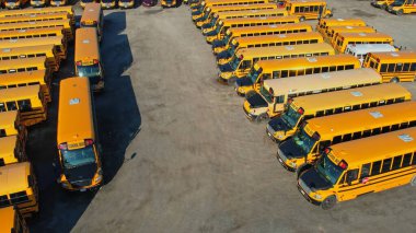 Toronto, Ontario, Canada - September 1, 2022: The parking full of school buses waiting for educational season. Row filled with many school bus ready to pick up students to school. Aerial view.