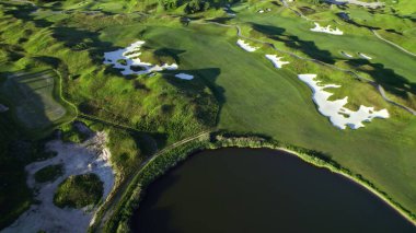Golf sahasının hava görüntüsü. Golf kulübünün üzerinde yeşillik vuruşu. Altın saat yaz günbatımı Uzun gölgeler.
