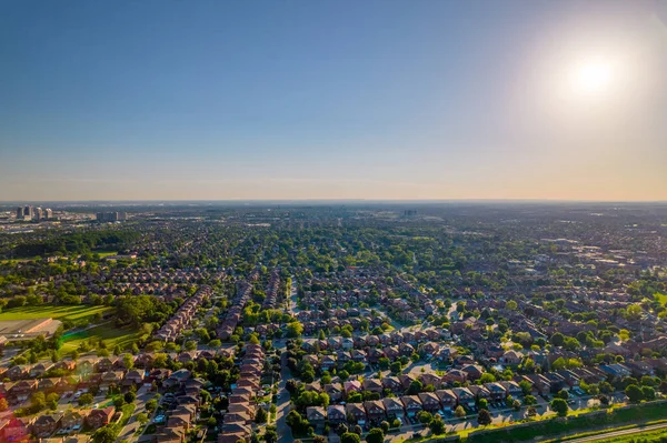 Aerial view of rich American citizens suburb at golden hour summer time. Established Real estate view of wealthy residential houses near greenery, parks and trees.
