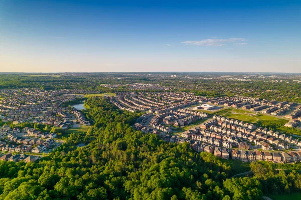 Aerial view of rich American citizens suburb at golden hour summer time. Established Real estate view of wealthy residential houses near greenery, parks and trees.