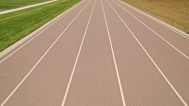 Açık hava spor stadyumundaki koşu pisti manzarasının üzerinde. Atletizm stadyumu ve koşu pisti boyunca yarışan atlet POV. Rekabet sporları ve şampiyon sıkı çalışma.