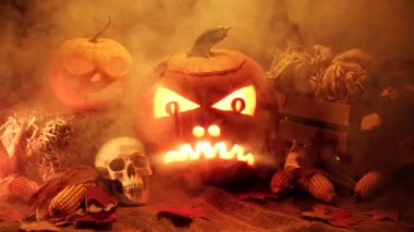 Balkabaklarının Cadılar Bayramı siyah arka planda geçiyor. Cadılar Bayramı ve hasat seti yabani otlar ve ahır çuvalı üzerinde insan kafatası ile. Ürkütücü şeytani ve ürkütücü sonbahar süslemeleri.