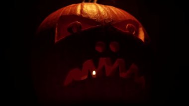Korkunç suratlı Cadılar Bayramı kabağı. Balkabağı Jack 'i kutluyoruz. Mum ışığında ve karanlıkta parlayarak..