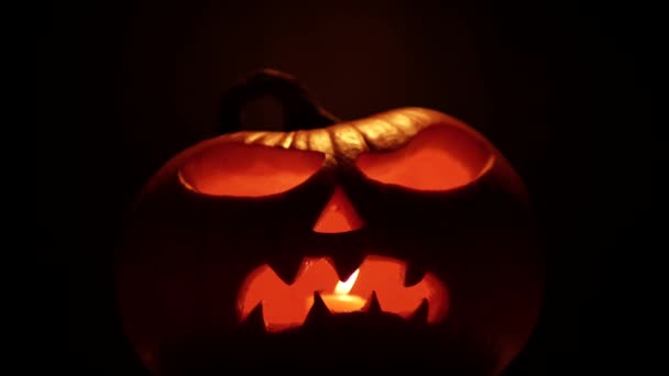 怖い顔をしたハロウィンカボチャ ろうそくの光と暗闇の中で輝くジャックOランタンカボチャを祝う — ストック動画