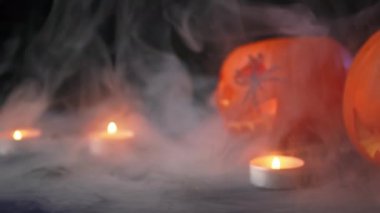 İki balkabağı dumanın içinde bir mum, arkasında karanlık bir arka plan, her yerde bir sis var, Cadılar Bayramı konsepti, korkunç sahneler, korku sahneleri.