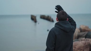 Genç adam tanıdıklarının dikkatini çekmek için elini sallıyor.