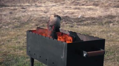 Wooden firewood flares up in a metal black brazier to then cook barbecue, shish kebab, kebab and other meat dish, outdoor recreation concept