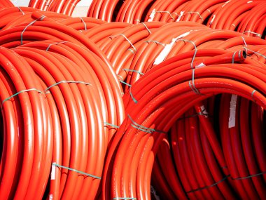Çok sayıda kırmızı pvc boru büyük rulo içine bükülmüş yalan, onarım konsepti, boru yenileme, depo, kıtlık