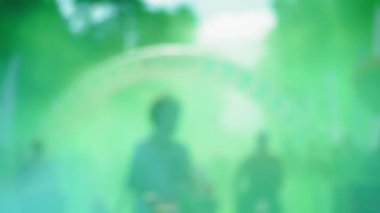 People run a marathon in green smoke from paint, people's faces are very blurred and you can't see them
