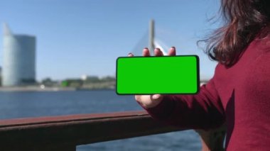 Kızın elinde yeşil ekran modeli olan bir cep telefonu var. Yüksek kalite 4k görüntü