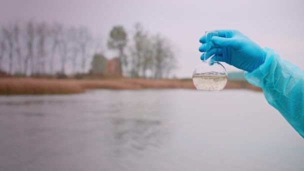Flacon Met Water Hand Blauwe Handschoen Tegen Achtergrond Van Reservoir — Stockvideo